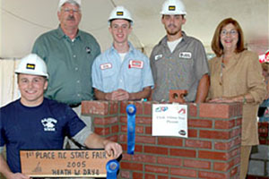 From left to right, champion Heath W. Drye, N.C. Commissioner of Agriculture Steven W. Troxler, third-place finisher Travis Greenly of McGee Brothers Company, second-place finisher Joshua Ferguson of Griffin Masonry, and N.C. Commissioner of Labor Cherie K. Berry.