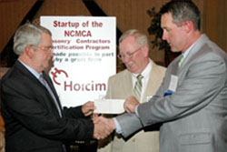 Holcim's Kenneth Duncan presents new NCMCA President Wayne Starr and Danks Burton the grant check.
