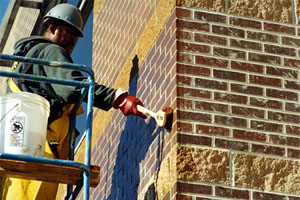 A worker gently scrubs a masonry wall. Gentle scrubbing is usually all that's needed if you're cleaning correctly. The masonry cleaner should do most of the work of dissolving contaminants. Photo courtesy of PROSOCO.