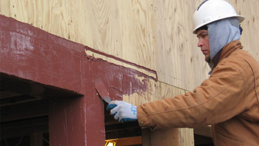 A worker completes the liquid-applied flashing of a rough opening, without having to use fabrics, tapes or wraps. Photo courtesy BEI.
