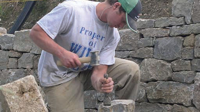 Grablewski shapes the stone for a retaining wall for a homeowner in Switzerland.