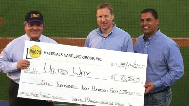 Jim Cieslar, executive director of United Way of Pitt County, accepts a check for $6,250 from Thom Peebles, NMHG director, brand management and Mike Moran, NMHG director, warehouse product sales, atop the East Carolina University dugout.