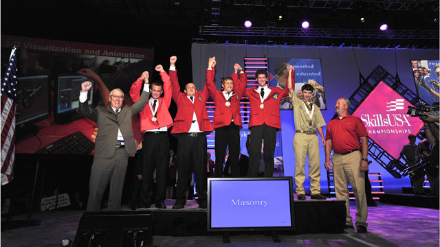 The winners of the 2012 National Masonry Contest at the 48th annual SkillsUSA National Leadership and Skills Conference took stage at Kemper Arena in Kansas City, Mo.  On the platform they are (l to r) high school / secondary winners Jacob Fulford (3rd), Pedro Menendez High School; McKenley McPeters (2nd), Pickens County Career and Technology Center; and Michael Kern (1st), Berks Career & Technical Center; followed by post secondary winners Jordan Hartsell (1st), Central Cabarrus High School; and Rody Feiler (3rd), Alexandria Technical & Community College. Flanking the winners are (left) Bryan Light, BIA SE Region and chair of the Masonry Technical Committee which organized contest; and (right) Todd Larson, Wisconsin Indianhead Technical College, representing the National Education Team.