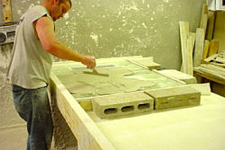 Employee screeds mortar into joints of pre-assembled panel