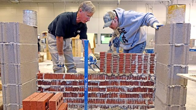 Bret Pickens, left, masonry instructor at Meridian Technology Center, talks with Gage Gibson, 19, a senior at Glencoe High School, as he learns to lay bricks stacked in a “soldier” design. Photo by David Bitton/Stillwater News Press.