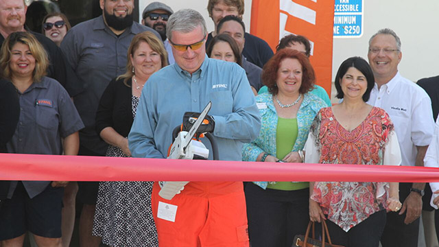 Larry Blamer, branch manager at Pacific STIHL, cuts the ribbon at new facility with STIHL MSA 200 C-BQ Lithium-Ion battery powered chainsaw.
