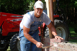 Green is shown constructing his latest masonry project — a lean-to storage shed built off the wall of an existing building to hide equipment from public view.