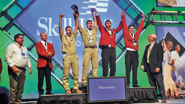 Winners of the 2010 National Masonry Contest at the 46th Annual SkillsUSA National Leadership and Skills Conference took stage at Kemper Arena in Kansas City, Mo. On the platform they are (l to r) third place winners Robert Gregory and Jacob Perkins; first place winners Brandon Boldon and Bradley Wright; and second place winner Matthew DiBara. Flanking the winners are Masonry Technical Committee members Bill Kjorlein (left) and Bryan Light (right).