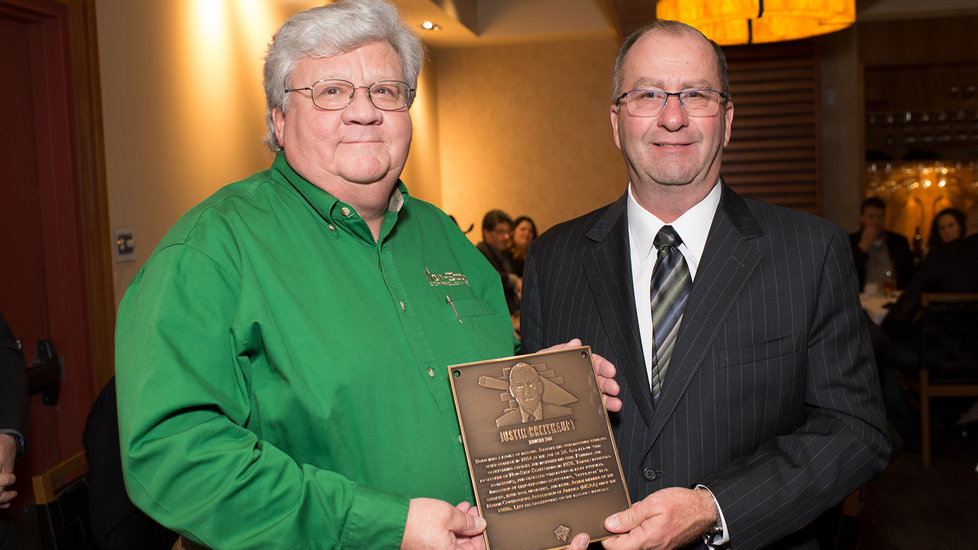 Justin Breithaupt, Jr. (left) accepts the Masonry Hall of Fame plaque on behalf of his father from MCAA Chairman Mike Sutter (right).