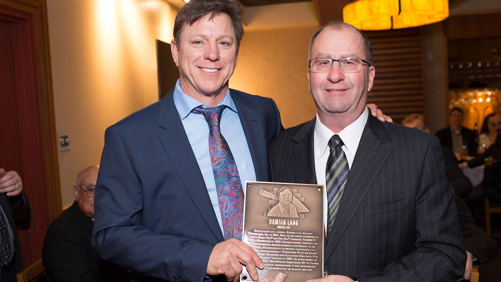 MCAA Chairman Mike Sutter (right) presents Damian Lang with his Masonry Hall of Fame plaque.