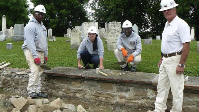 Students in the brick masonry program at Iroquois Job Corps are repairing a deteriorating stone wall at Shelby Cemetery. From left are Ezekiel McAllister of Brooklyn, Sara Huey of Tonawanda, Ibrahim Abdul of New York City and instructor Marty Bryant.