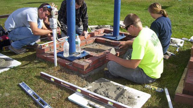 Students with the Maine School of Masonry build a brick planter for the Living Waters of God church on the Wilton Road.